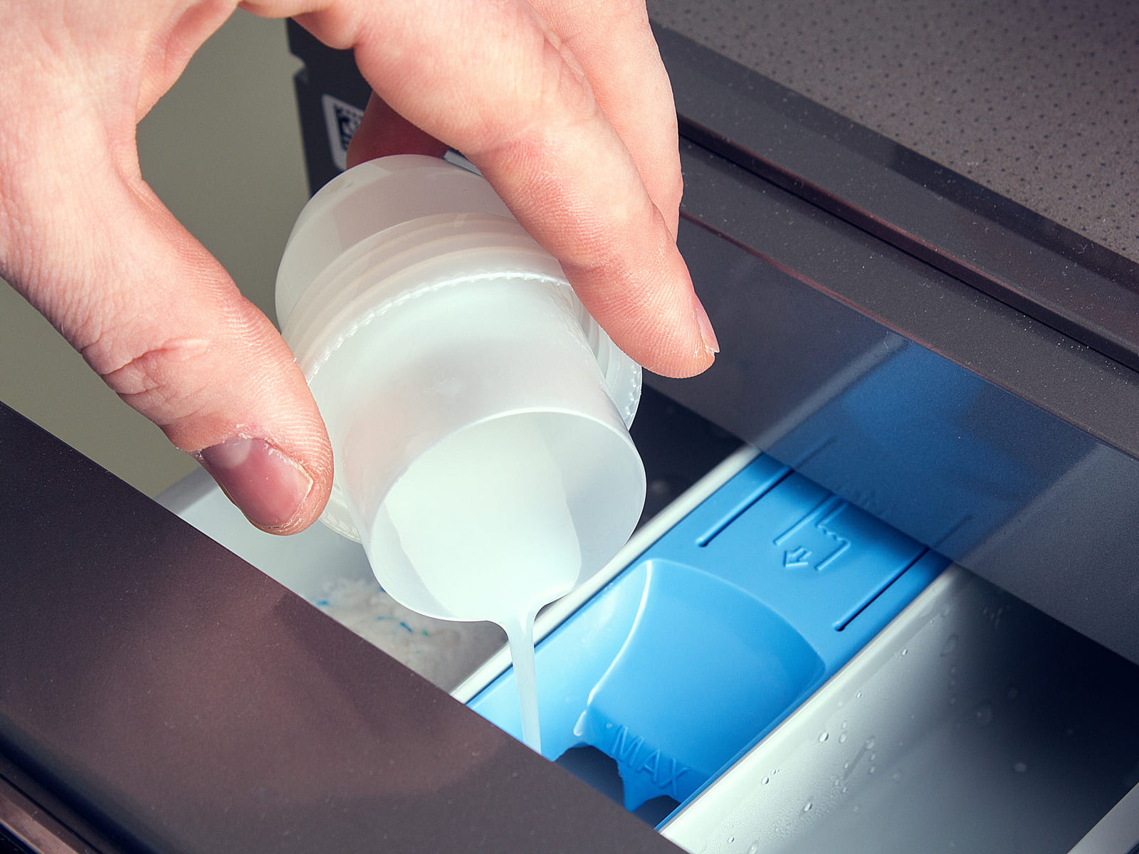 image of someone pouring fabric softener into a washer machine