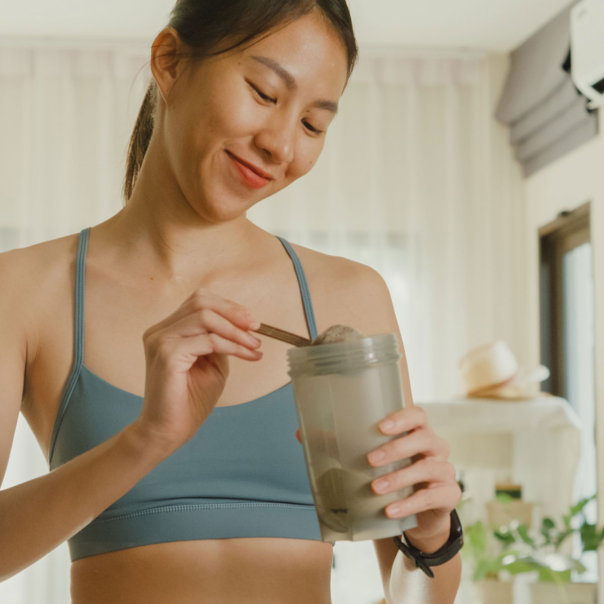 woman adding powder to a shaker bottle