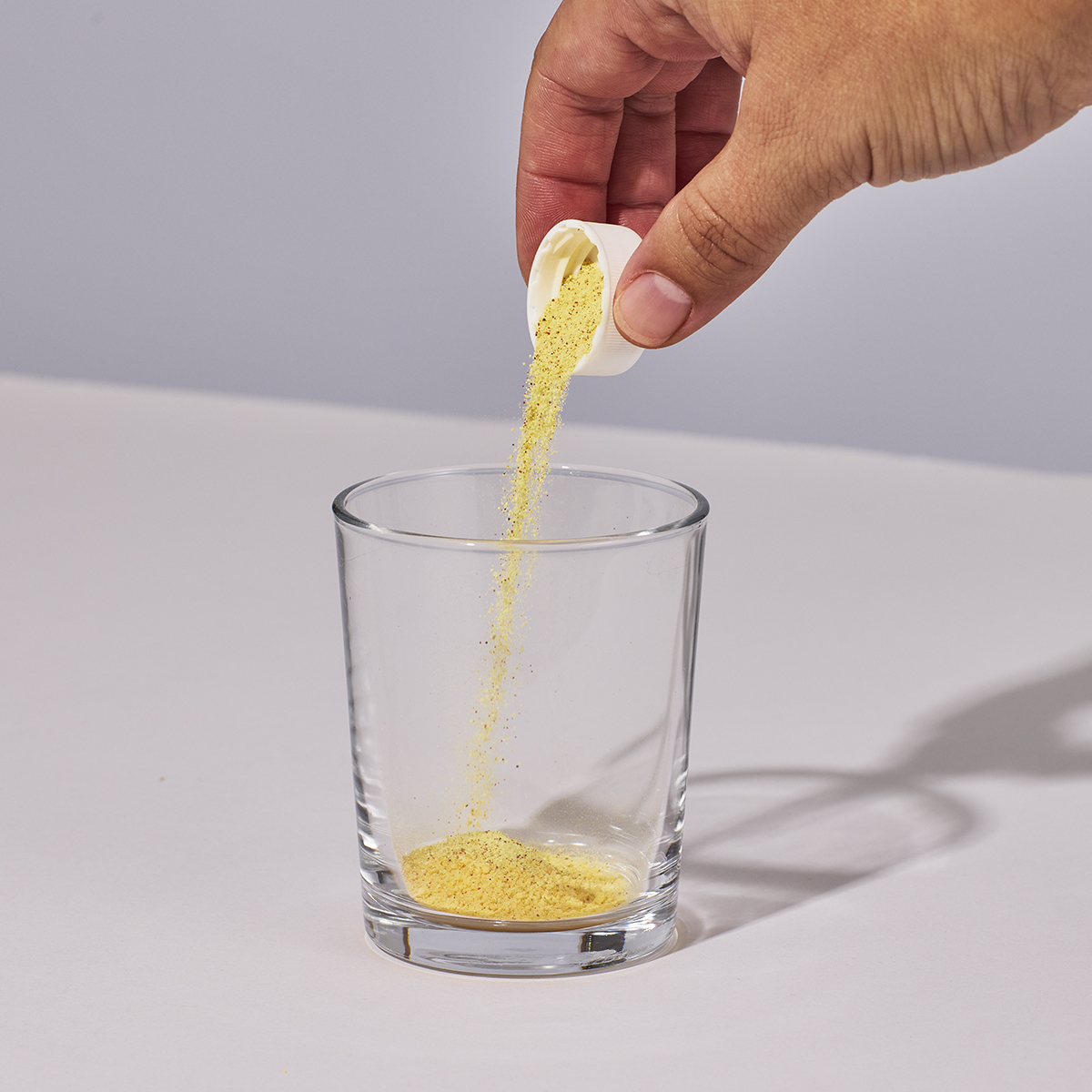 image of person pouring on cap of Isotonix Vision Formula with Lutein powder into a glass