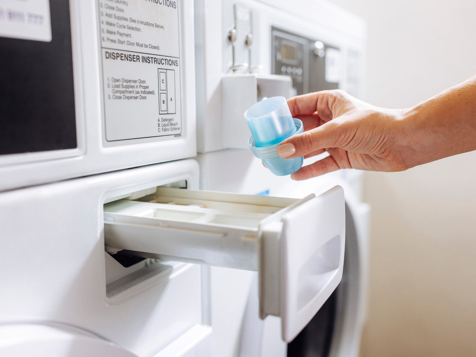 image of someone pouring laundry detergent into a washing machine
