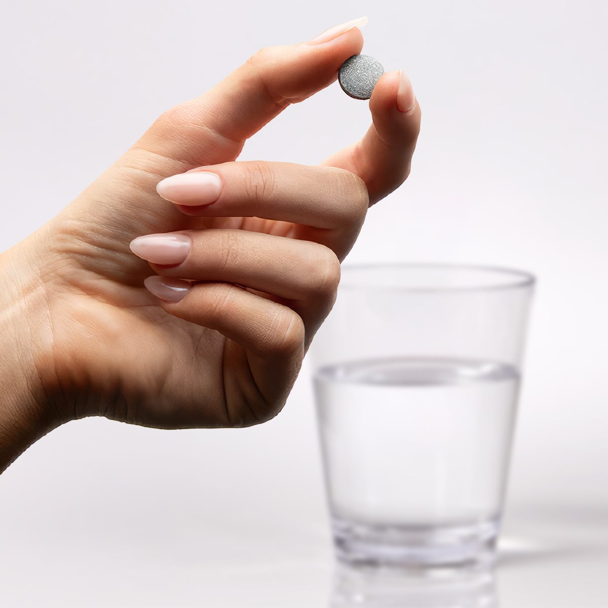 image of hand holding H2TAB in front of glass of water