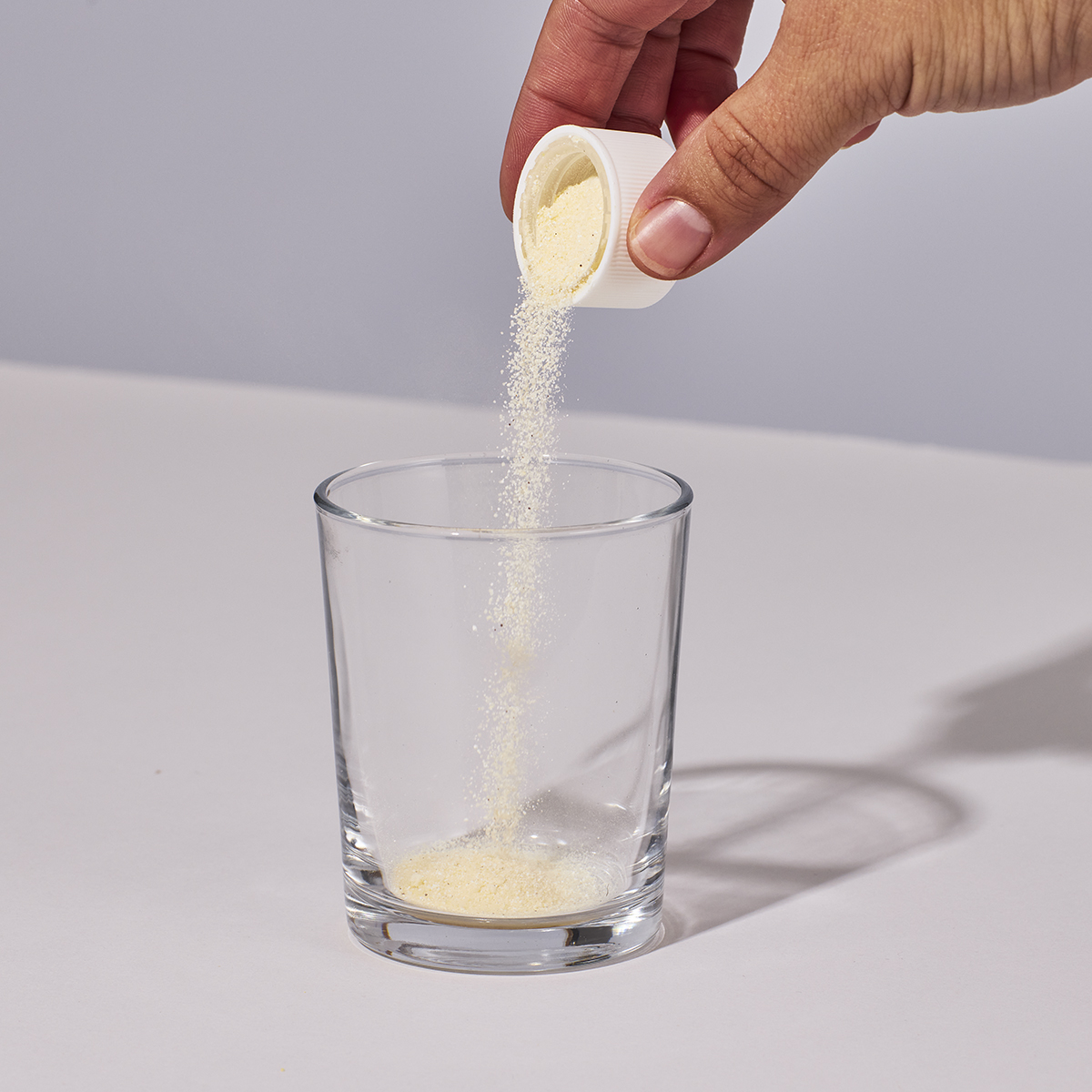 Image of person pouring a capful of Isotonix Prenatal Activated Multivitamin into a glass.