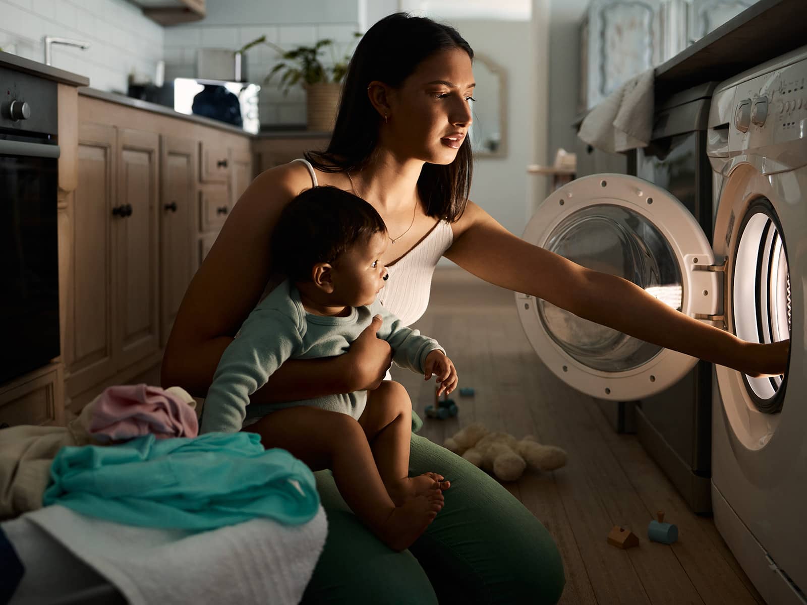 person with baby loading the washer machine