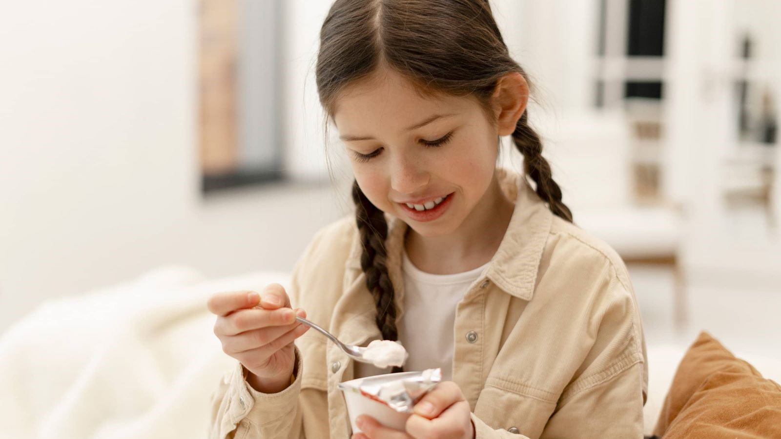 image of girl smiling and eating yogurt