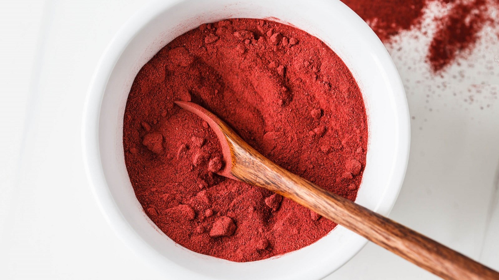 image of white bowl of astaxanthin powder with wooden spoon