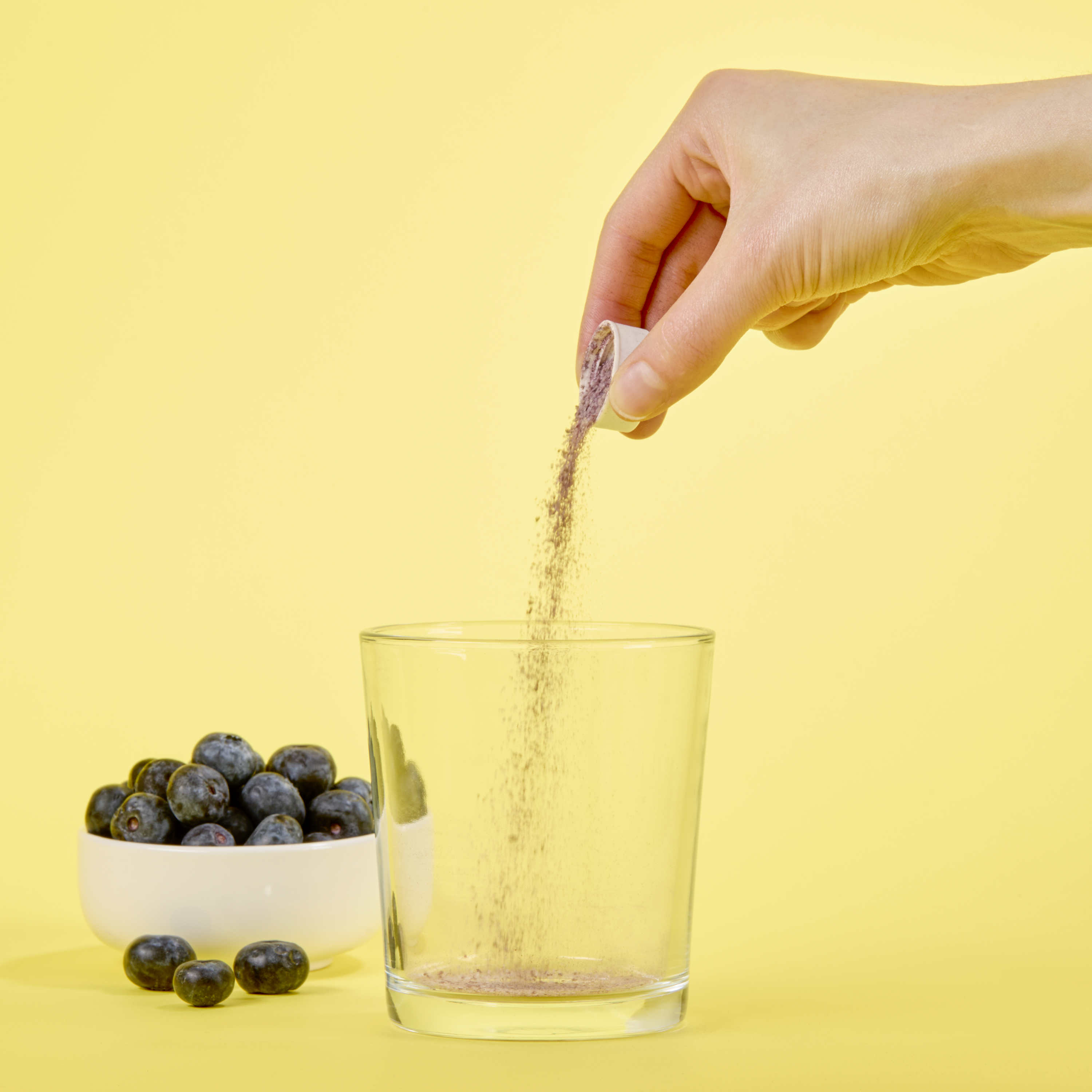 image of person adding capful of powder to glass