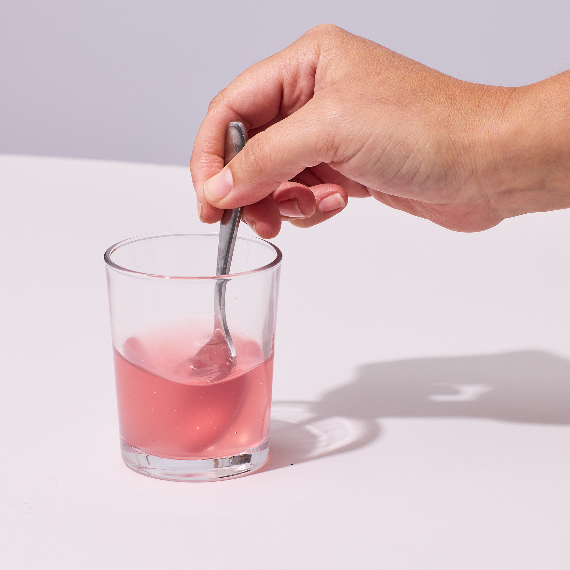 Person stirring powder and water in glass