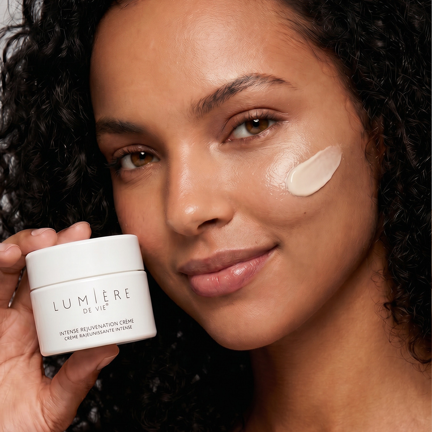 women is holding the lotion jar and has cream swatch on face