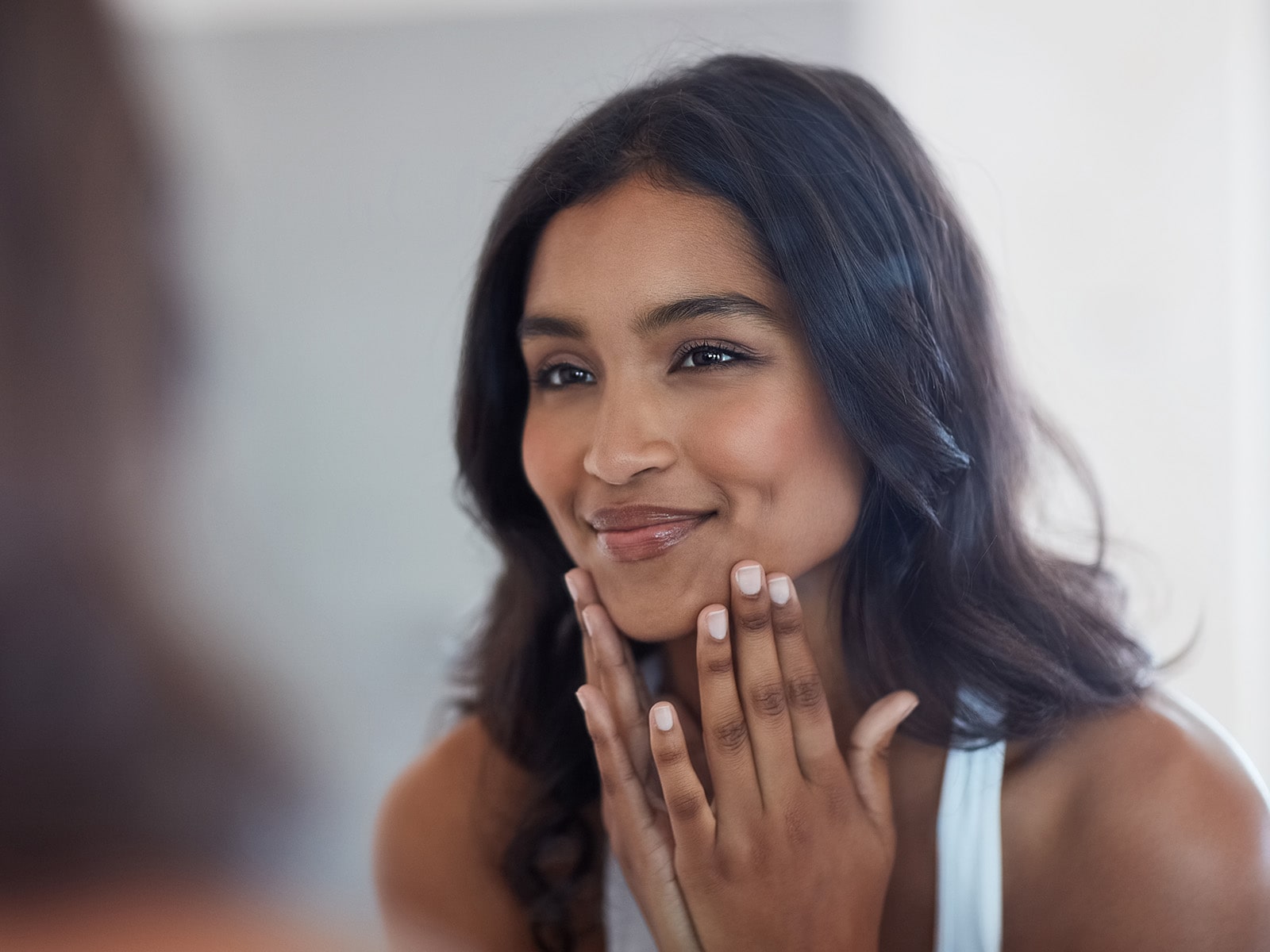 image of a person with healthy skin looking into a mirror