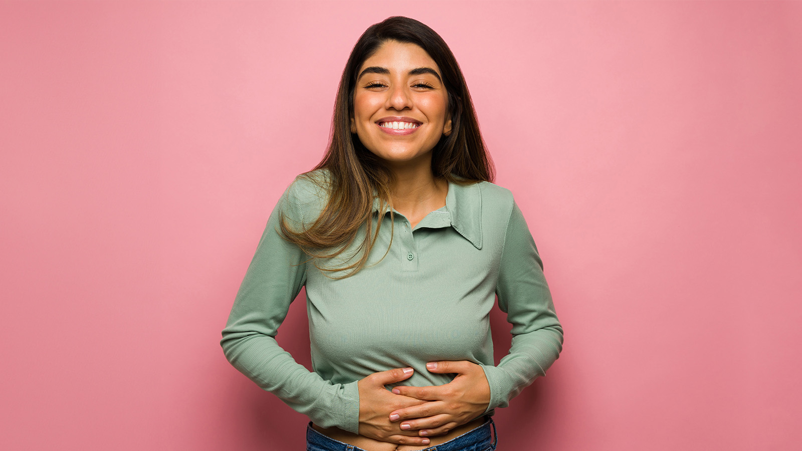 image of a woman smiling and holding her stomach