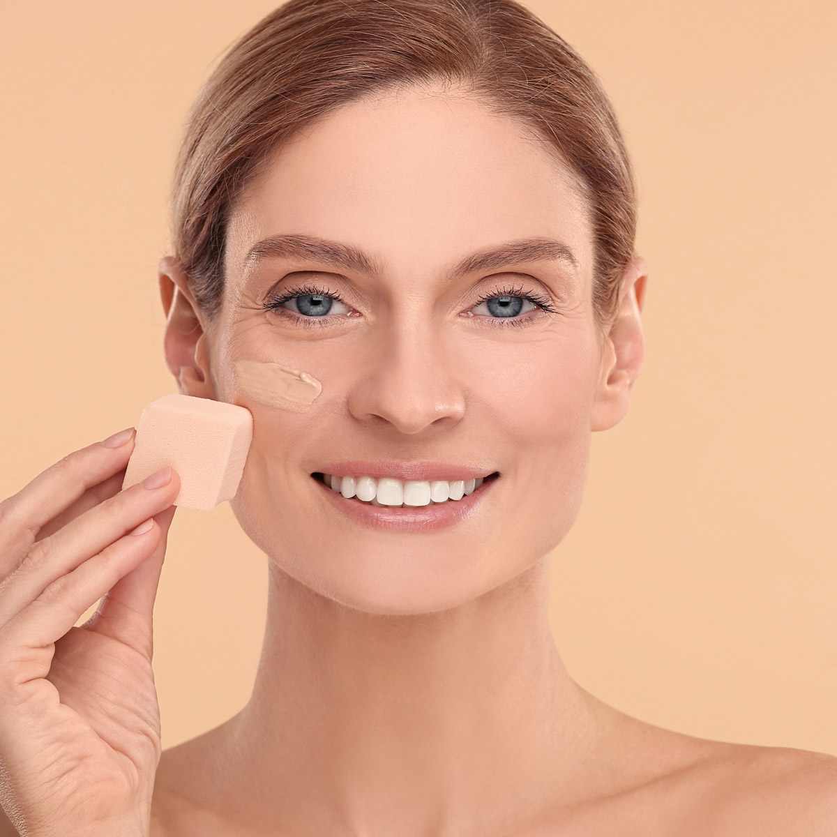 women is using sponge blending foundation on face