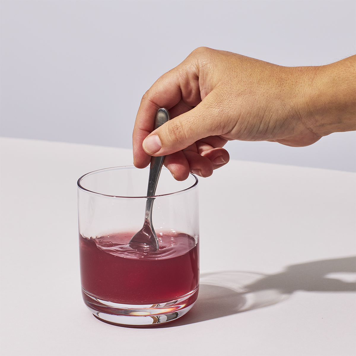image of a a hand mixing one serving of Isotonix Acai powder with water